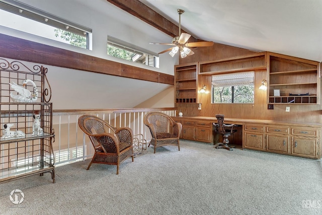 carpeted home office with wooden walls, a ceiling fan, vaulted ceiling with beams, and built in study area