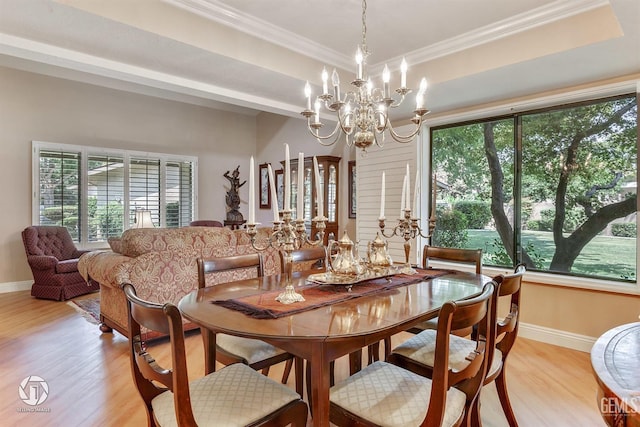 dining room with ornamental molding, light wood-style floors, baseboards, a tray ceiling, and a chandelier