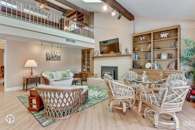 living area featuring beamed ceiling, visible vents, track lighting, and wood finished floors