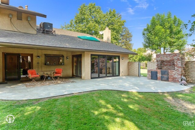 back of property with central air condition unit, a patio area, stucco siding, and a yard