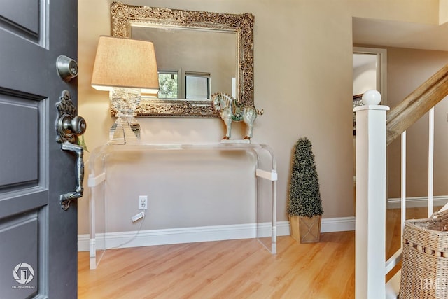 foyer entrance with baseboards, wood finished floors, and stairway