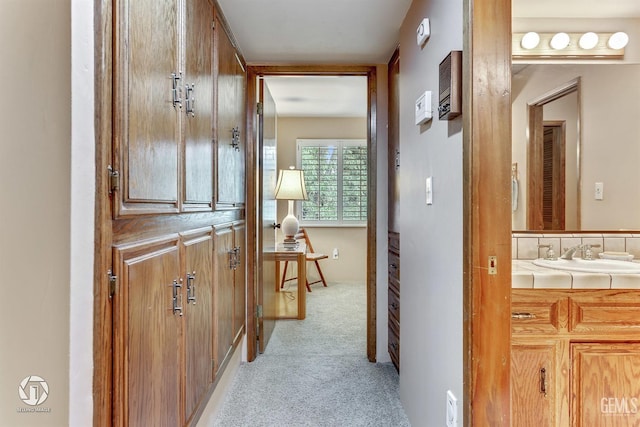 corridor with a sink and light carpet
