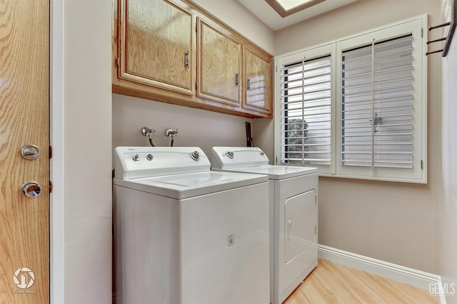 laundry room featuring baseboards, washing machine and dryer, light wood finished floors, and cabinet space