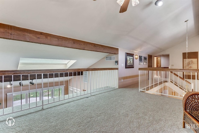 interior space featuring carpet, a ceiling fan, lofted ceiling with skylight, and visible vents