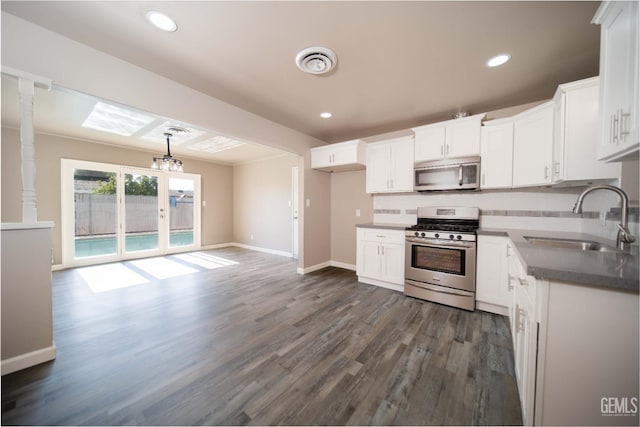 631 Union St, Delano, CA 93215 - kitchen with stainless steel appliances, a sink, baseboards, dark wood-type flooring, and white cabinets