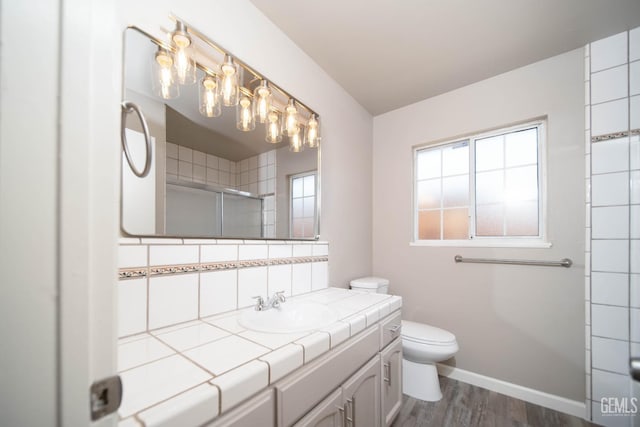 631 Union St, Delano, CA 93215 - bathroom featuring a shower with shower door, toilet, wood finished floors, vanity, and tasteful backsplash