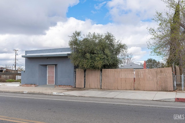 view of front facade with fence, a gate, and stucco siding