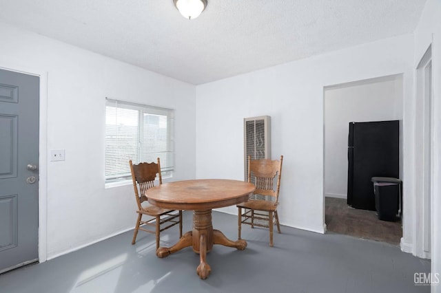 dining space featuring finished concrete floors, baseboards, and a textured ceiling