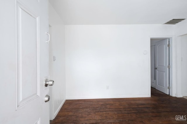 unfurnished room featuring baseboards, visible vents, and wood finished floors