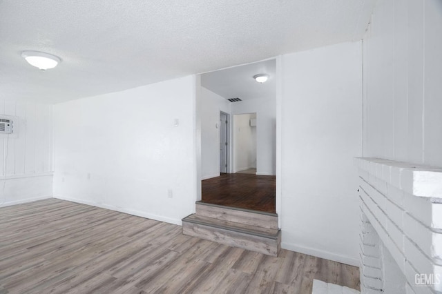 unfurnished room featuring visible vents, a textured ceiling, baseboards, and wood finished floors