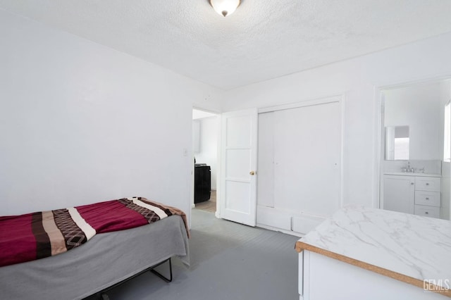 bedroom featuring a textured ceiling, a closet, a sink, and concrete flooring