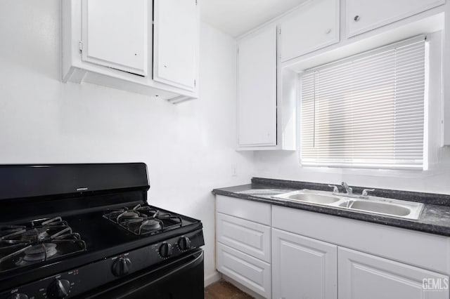 kitchen featuring black range with gas cooktop, white cabinetry, and a sink