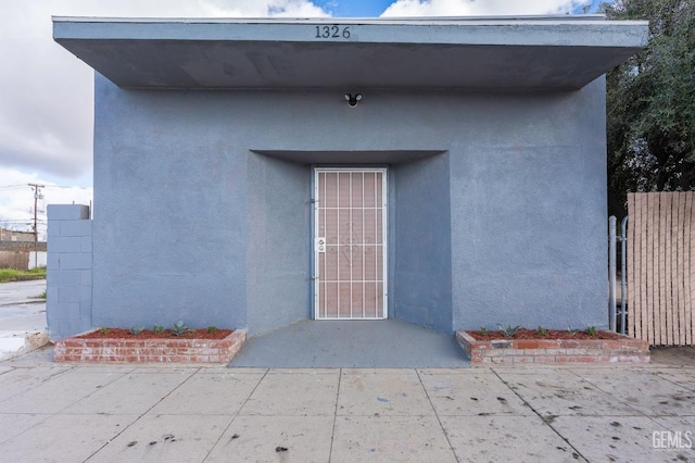 property entrance featuring fence and stucco siding