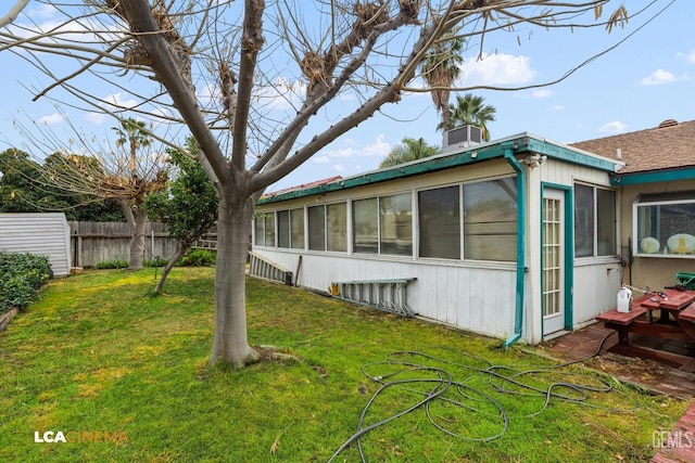 view of property exterior featuring a yard, a chimney, fence, and a sunroom