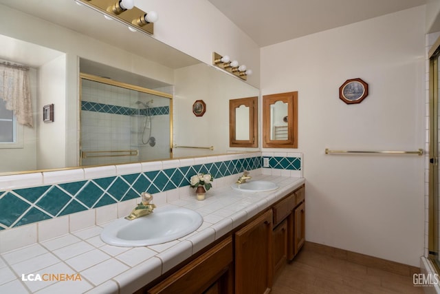 full bathroom featuring double vanity, a stall shower, decorative backsplash, and a sink