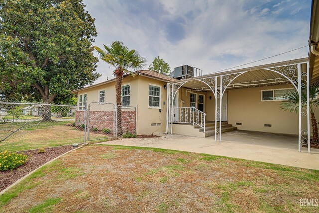 back of house featuring central AC, fence, stucco siding, a gate, and crawl space