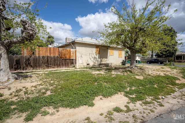 view of front of home with stucco siding, fence, and crawl space