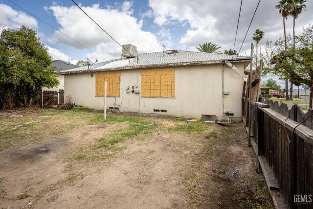 rear view of property with stucco siding, fence, and crawl space