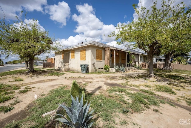 view of side of home with stucco siding and fence