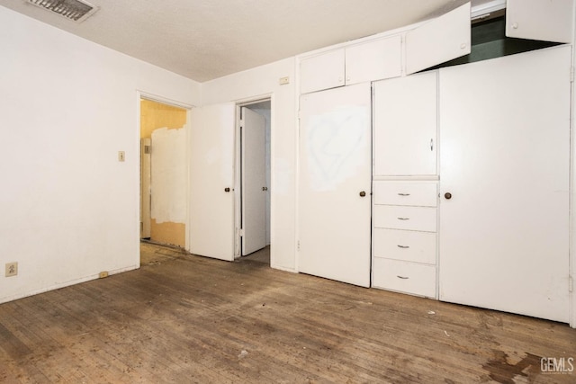 unfurnished bedroom with visible vents, a closet, and wood finished floors