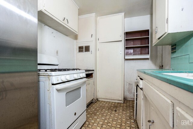 kitchen with light countertops, white cabinetry, light floors, visible vents, and white range with gas stovetop