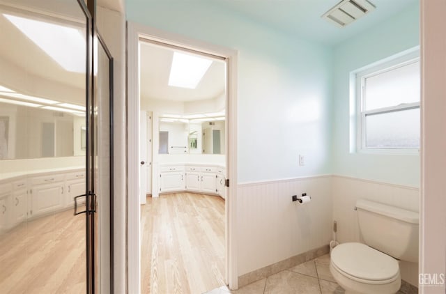 7001 Eloy Ave, Bakersfield, CA 93308 - full bath with visible vents, toilet, wood finished floors, vanity, and wainscoting