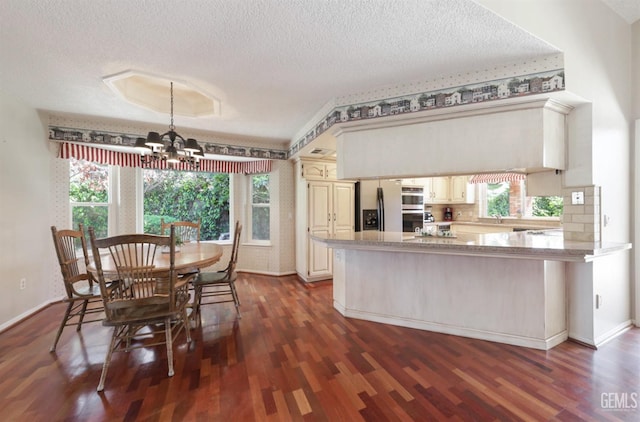 7001 Eloy Ave, Bakersfield, CA 93308 - kitchen featuring a sink, appliances with stainless steel finishes, a peninsula, dark wood-style floors, and an inviting chandelier