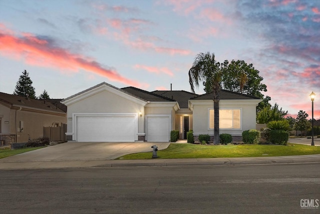 single story home featuring a garage, concrete driveway, a lawn, and stucco siding