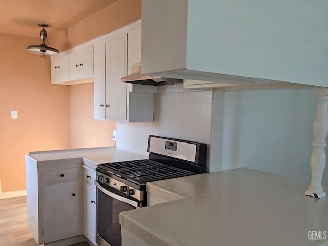 kitchen with white cabinets, kitchen peninsula, light hardwood / wood-style floors, and stainless steel gas range oven