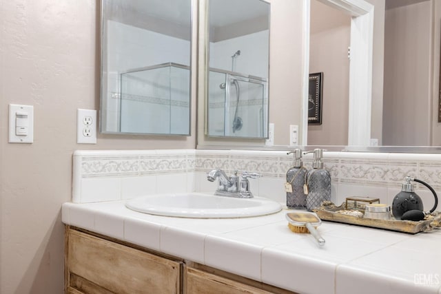 bathroom featuring decorative backsplash, an enclosed shower, and vanity