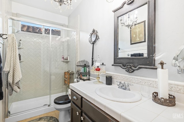 bathroom featuring tile patterned floors, vanity, toilet, a notable chandelier, and a shower with shower door