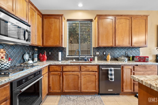 kitchen with light tile patterned floors, sink, appliances with stainless steel finishes, and tasteful backsplash