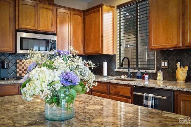 kitchen featuring light stone countertops, dishwasher, sink, and tasteful backsplash