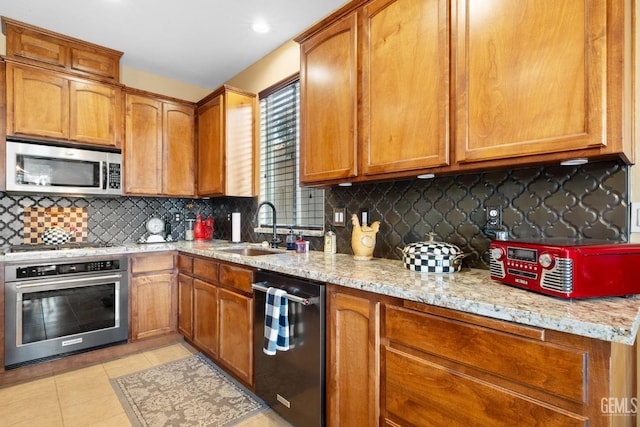 kitchen with sink, light stone counters, appliances with stainless steel finishes, and tasteful backsplash