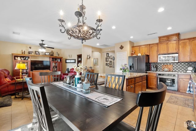 tiled dining area featuring ceiling fan with notable chandelier