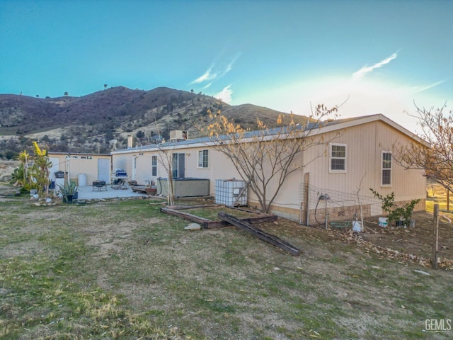 rear view of house featuring a mountain view, a patio, and a jacuzzi