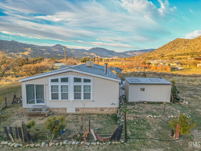 view of side of home featuring a mountain view and an outdoor structure