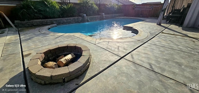 view of swimming pool with a patio, pool water feature, and an outdoor fire pit