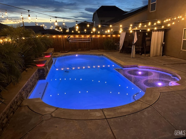 pool at dusk with an in ground hot tub