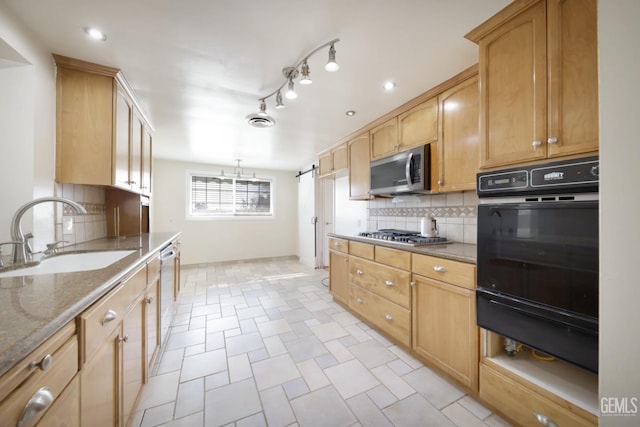 kitchen featuring appliances with stainless steel finishes, stone countertops, sink, a chandelier, and decorative backsplash