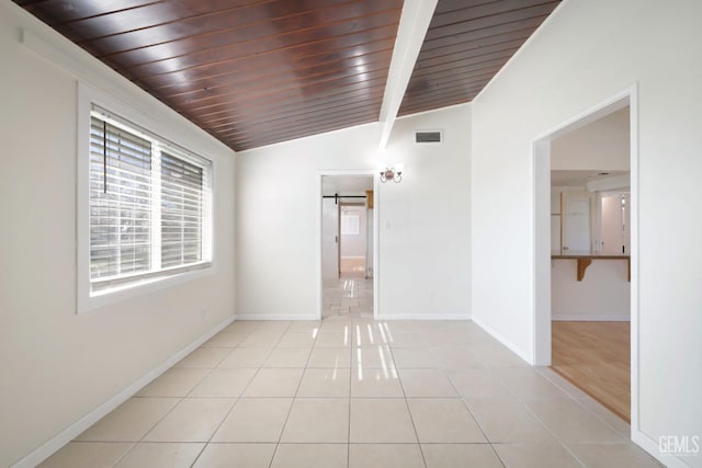 unfurnished room featuring light tile patterned floors, lofted ceiling with beams, a barn door, and wooden ceiling