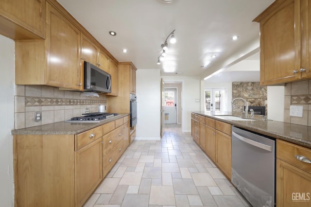 kitchen featuring appliances with stainless steel finishes, sink, backsplash, dark stone counters, and french doors