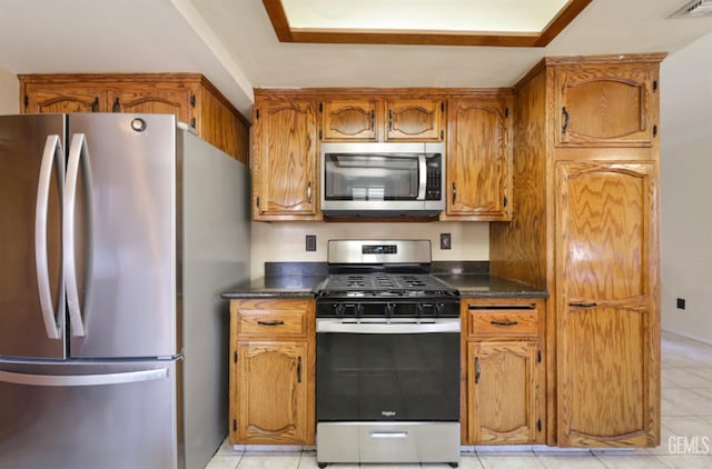 1107 Mcginley Ave, Bakersfield, CA 93308 - kitchen with stainless steel appliances, dark countertops, brown cabinets, and light tile patterned flooring