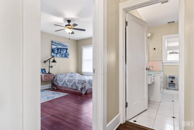 bedroom featuring ceiling fan, heating unit, and light hardwood / wood-style floors