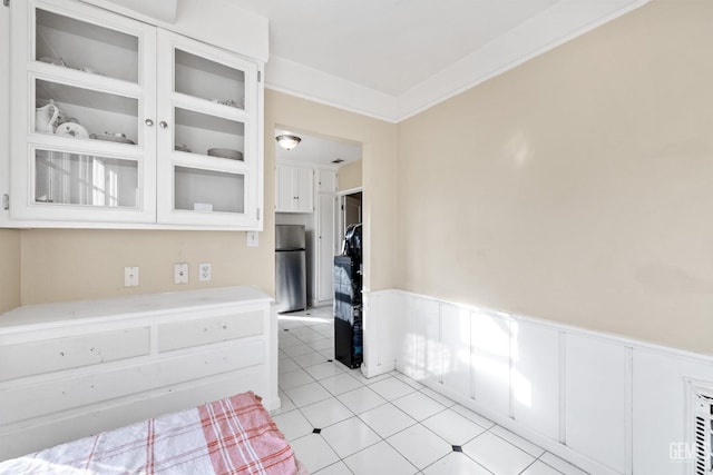 interior space featuring white cabinetry, ornamental molding, and stainless steel refrigerator