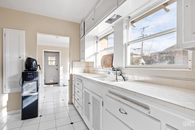 kitchen featuring white cabinetry, sink, light tile patterned floors, and backsplash