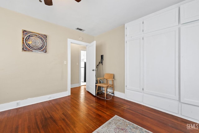 unfurnished bedroom with ceiling fan, dark hardwood / wood-style floors, refrigerator, and a closet