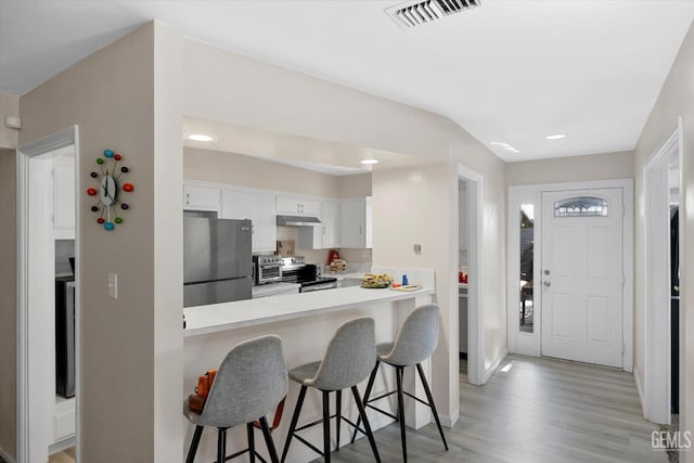 941 Panorama Dr, Bakersfield, CA 93305 - kitchen with stainless steel appliances, a breakfast bar area, light countertops, light wood finished floors, and white cabinetry