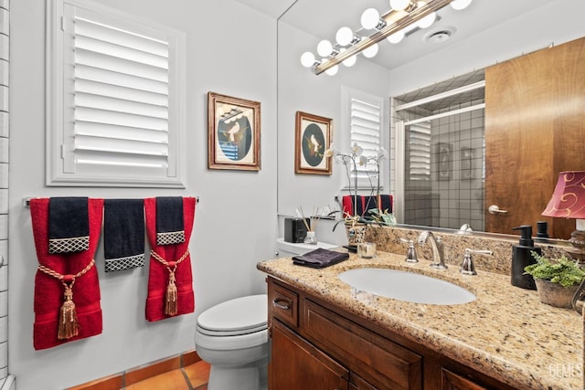 bathroom featuring tile patterned flooring, vanity, toilet, and a shower with door