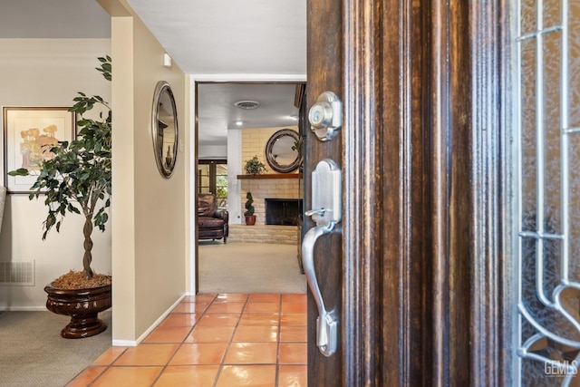 carpeted foyer with a brick fireplace